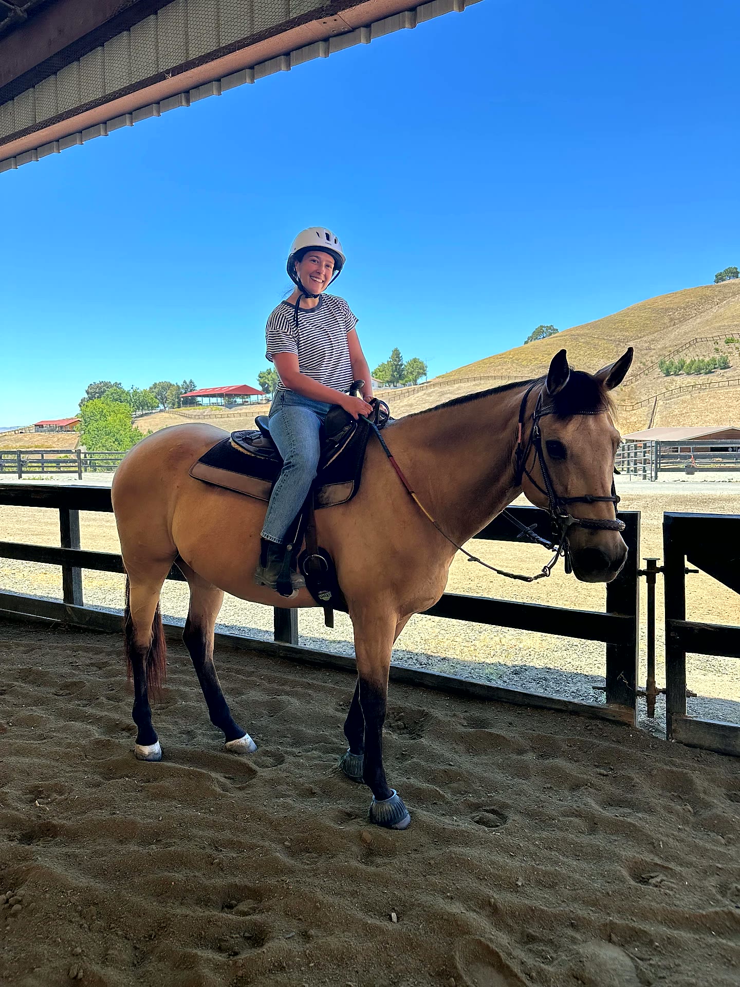 Smiling rider mounted in a western saddle with the Pleasanton hills behind