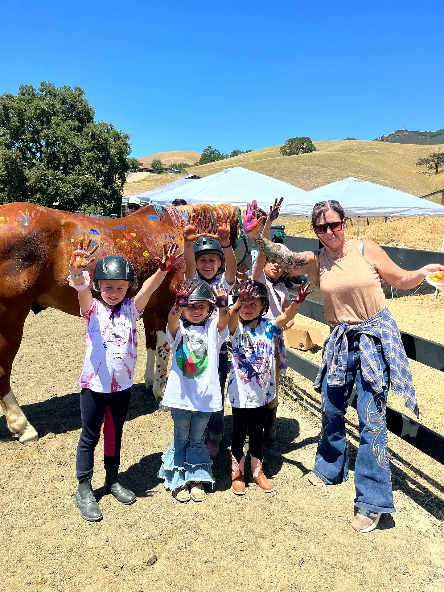 Camp group with instructor and painted horse under sunny Pleasanton hills