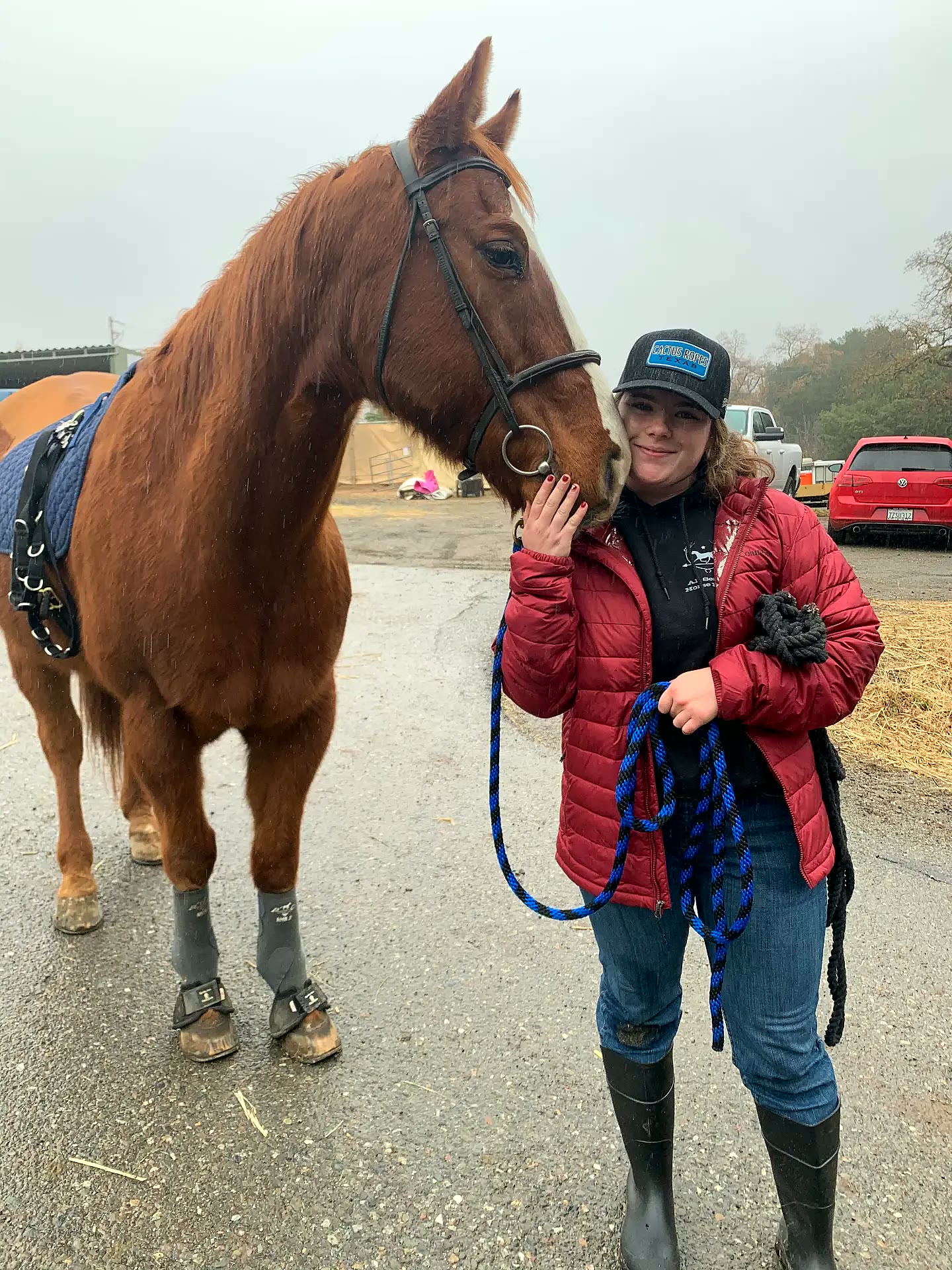Rider hugging her horse's nose on a rainy barn morning